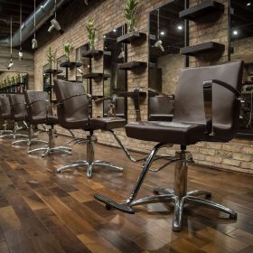 Row of brown salon chairs under suspended weightless dryers at Black the Salon in Royal Oak