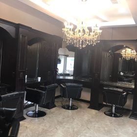 Another angle of salon chairs beneath chandeliers and mirrors