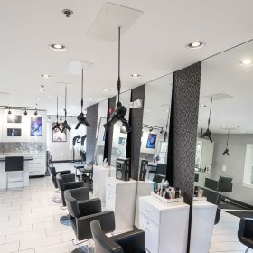View of mirrored salon stations with hanging dryers