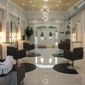Salon interior showing multiple stations with ceiling-mounted dryers